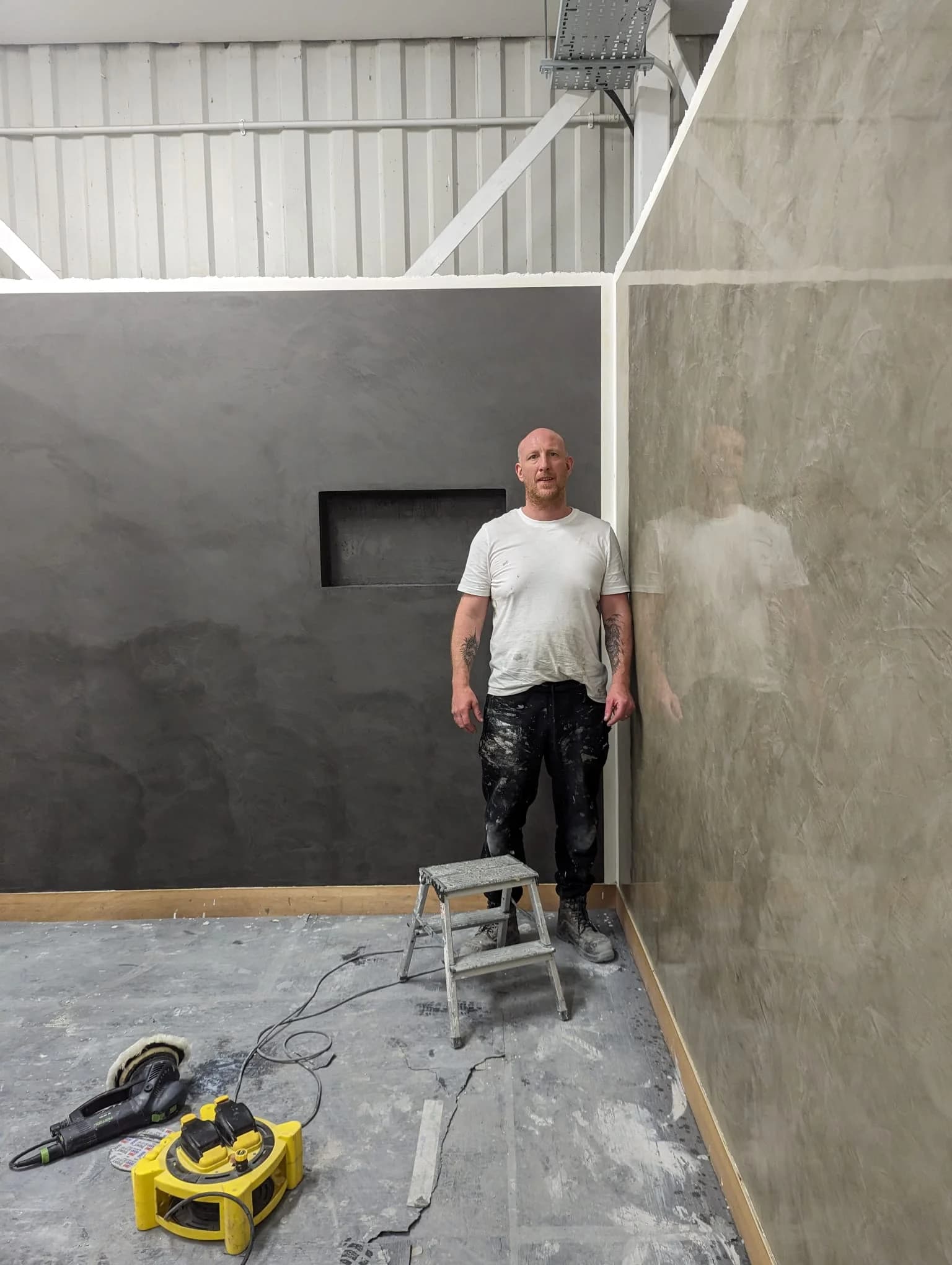 Plasterer standing beside a high gloss reflective polished plaster wall
